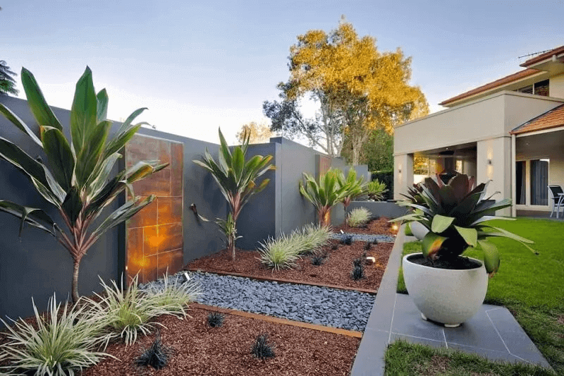 Professional gardener planting native Australian plants in freshly mulched garden beds