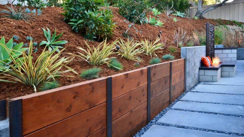 Professionally constructed timber sleeper retaining wall with integrated garden beds