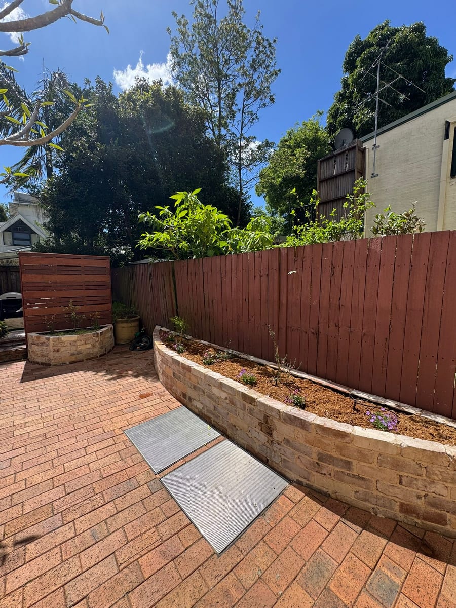 Curved recycled brick planter beside a paved courtyard in Glebe